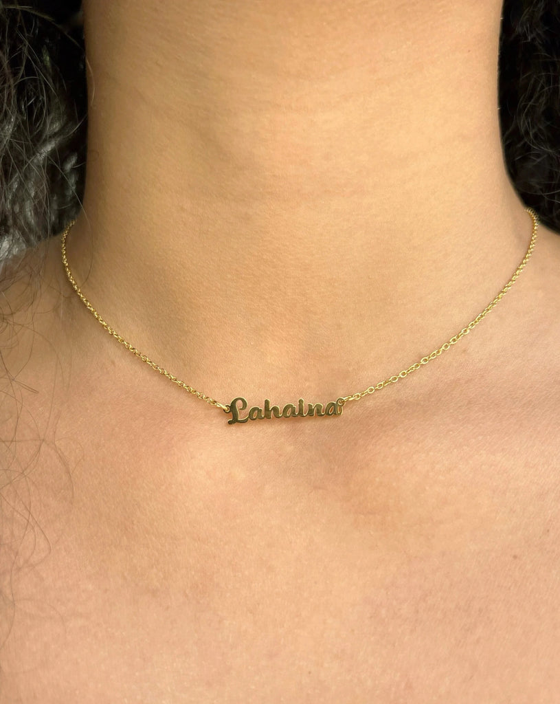 Gold necklace writing Lahaina in cursive.