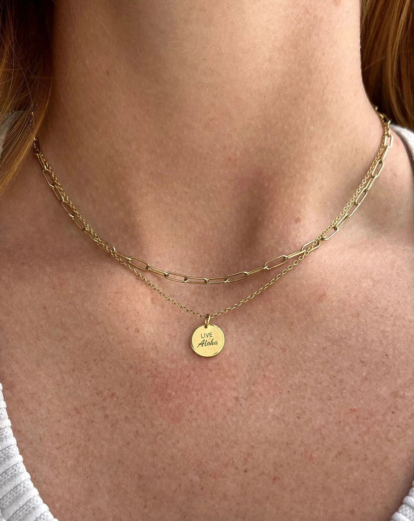 This gold plated, waterproof necklace features a small round pendant charm with LIVE ALOHA etched in the center. 